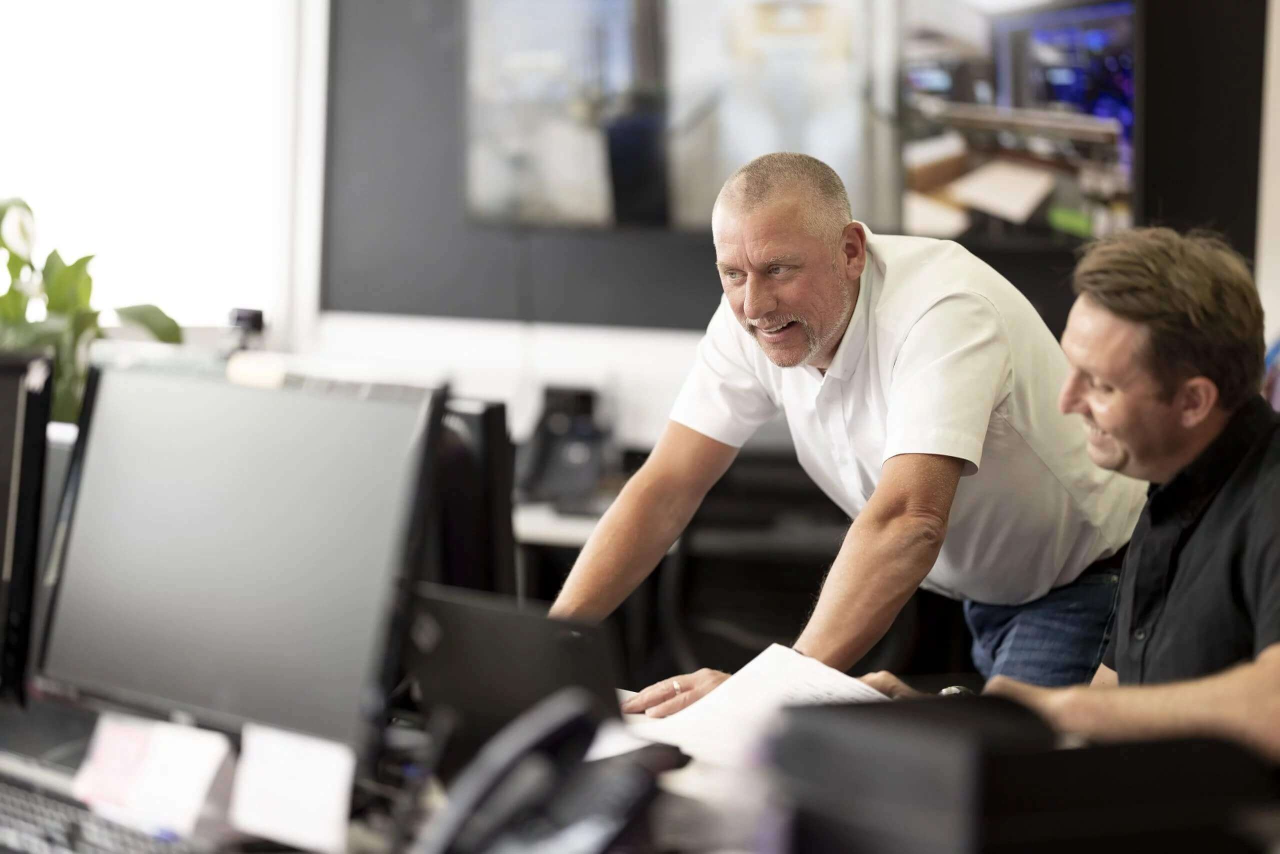 2 men looking at a computer together.